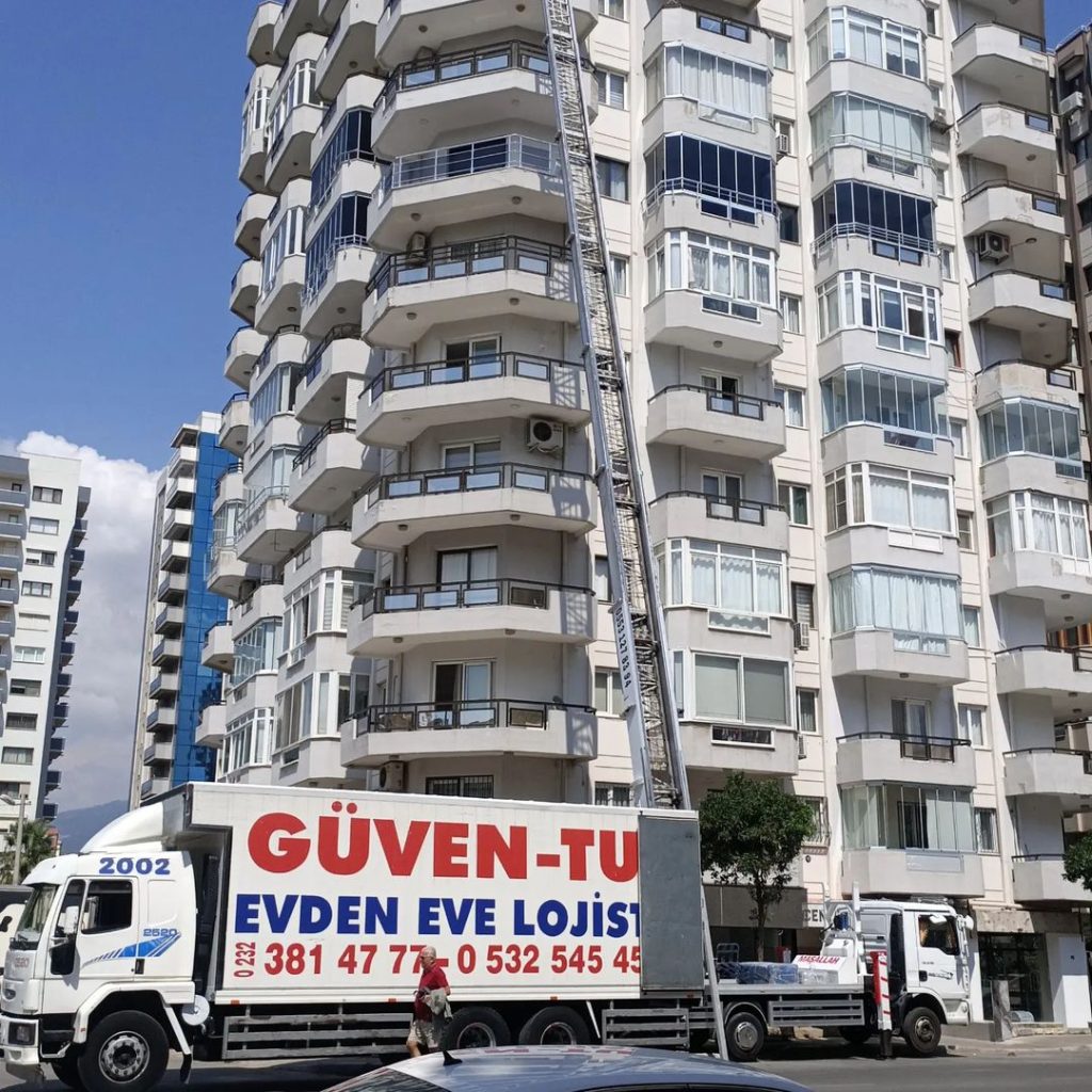 Güven-Tur kamyonu ve yüksek katlı apartmanın cephesine kurulmuş eşya asansörü